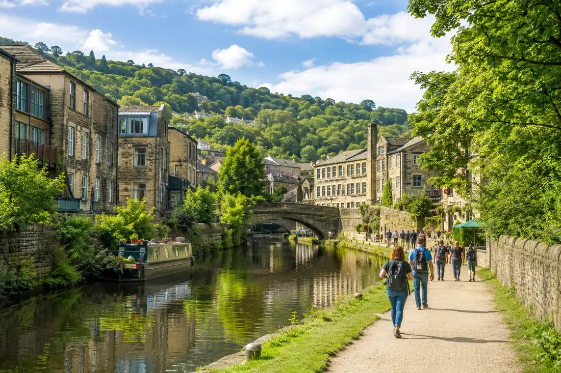 People exploring Hebden Bridge beside the canal with stone buildings, narrowboats and green hills, ideal for a self-guided walking tour.