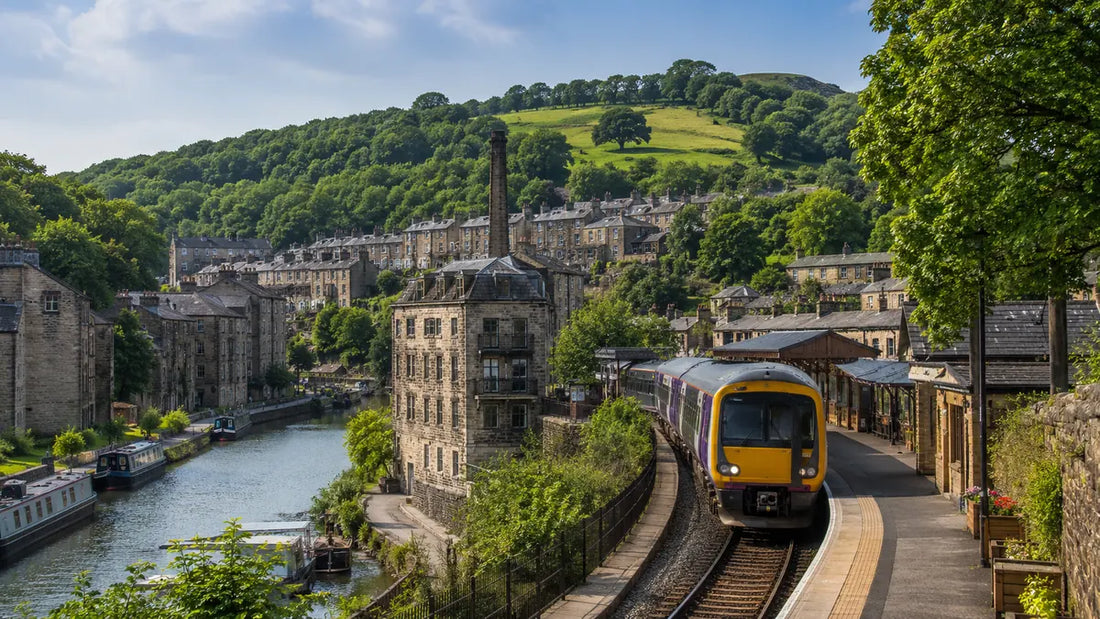 Train arriving at Hebden Bridge railway station beside the canal, stone buildings and green hills in West Yorkshire.